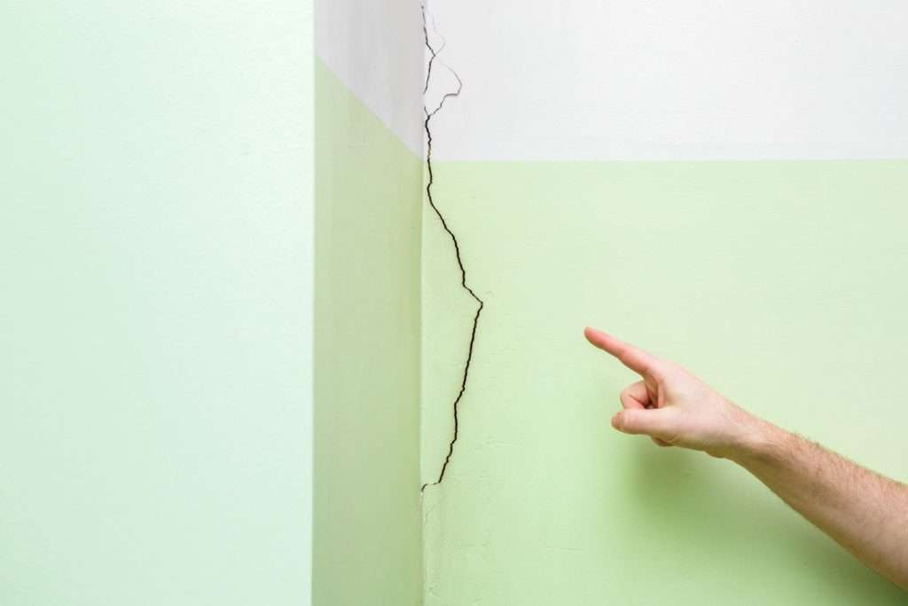 Image showing a hand pointing at a crack in a wall.